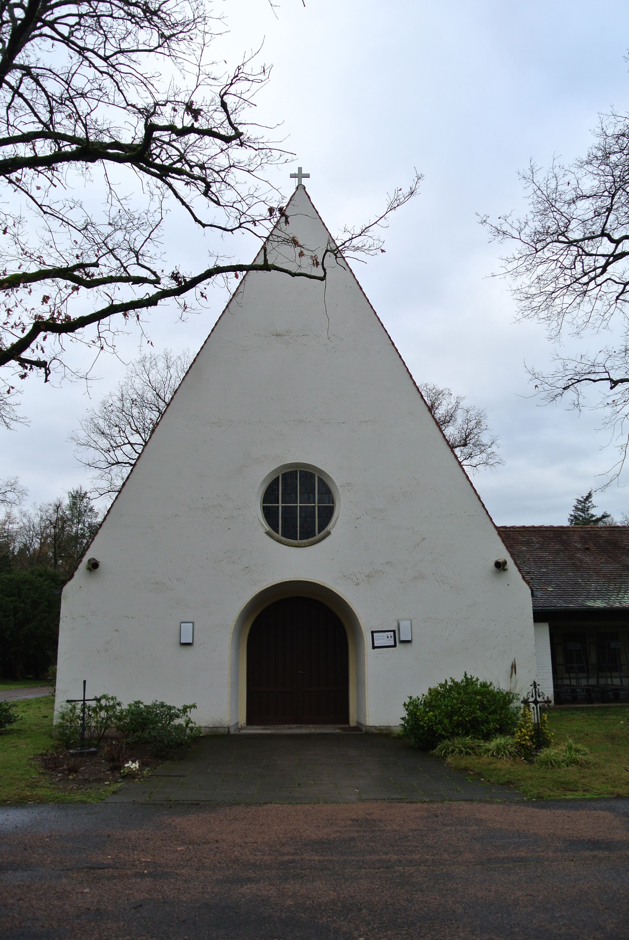 Weiße Trauerhalle mit steilem Giebel auf dem Waldfriedhof Goldstein